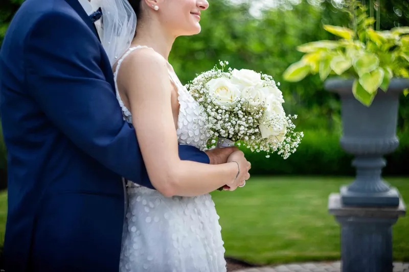 La mariée et son bouquet blanc dans les bras du marié.