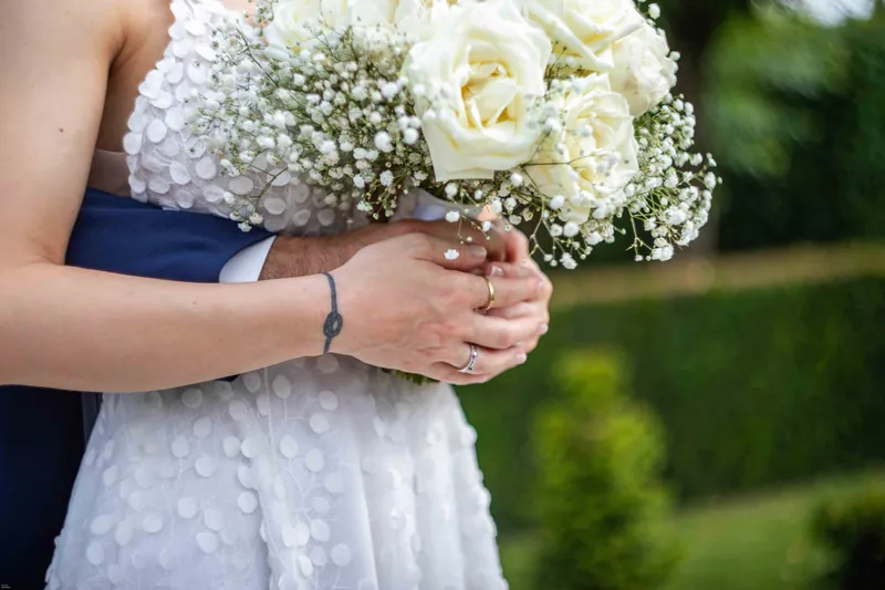 Détail du bouquet de roses blanches et de gypsophile contre la robe.