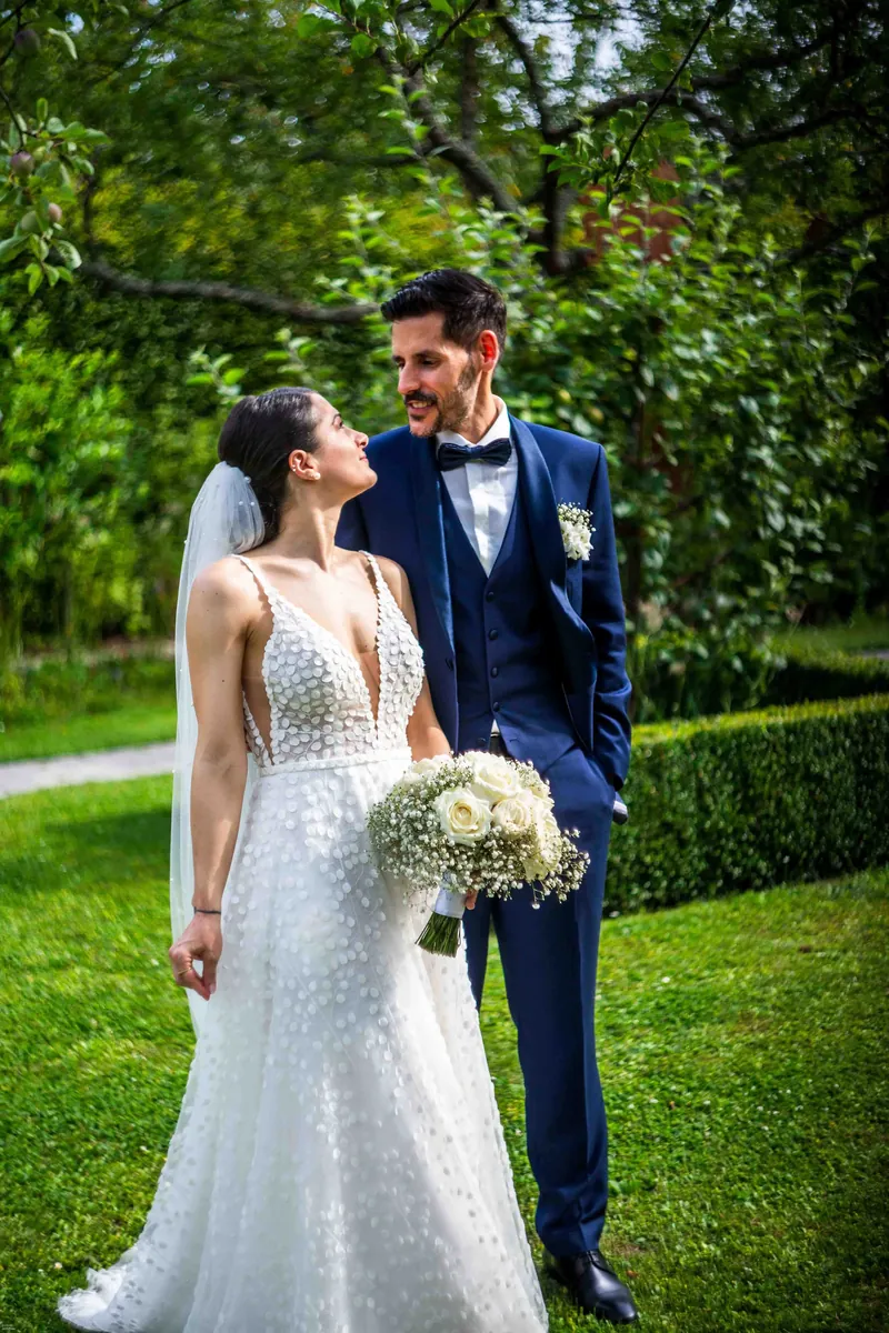 Les mariés dans un jardin, la mariée en robe brodée.