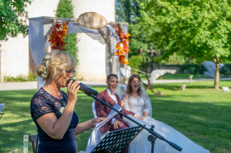 Une proche prononce un discours au micro pendant la cérémonie laïque en plein air.