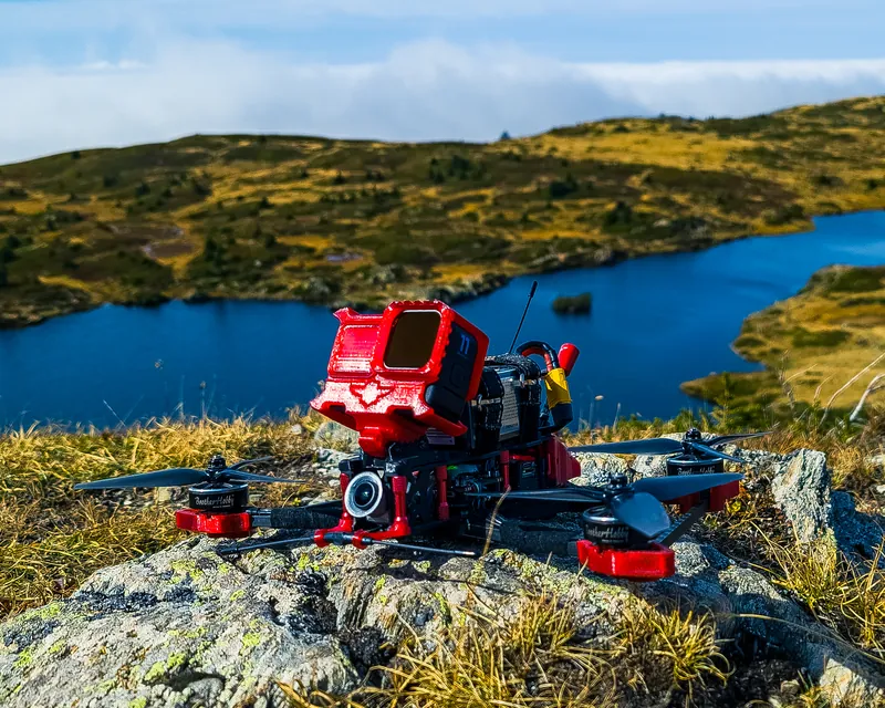 Drone FPV posé sur un rocher au-dessus d’un lac de montagne.