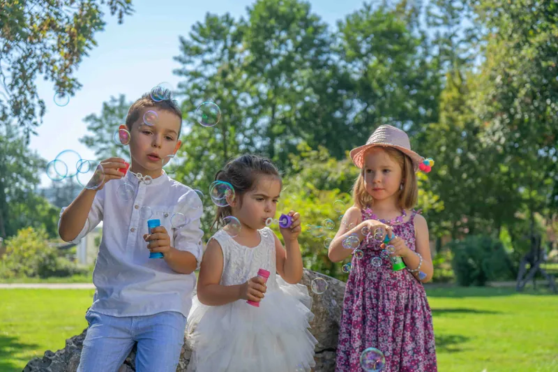 Trois enfants d’honneur soufflent des bulles de savon dans le parc.