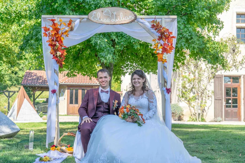 Les mariés assis sous l’arche de cérémonie décorée.