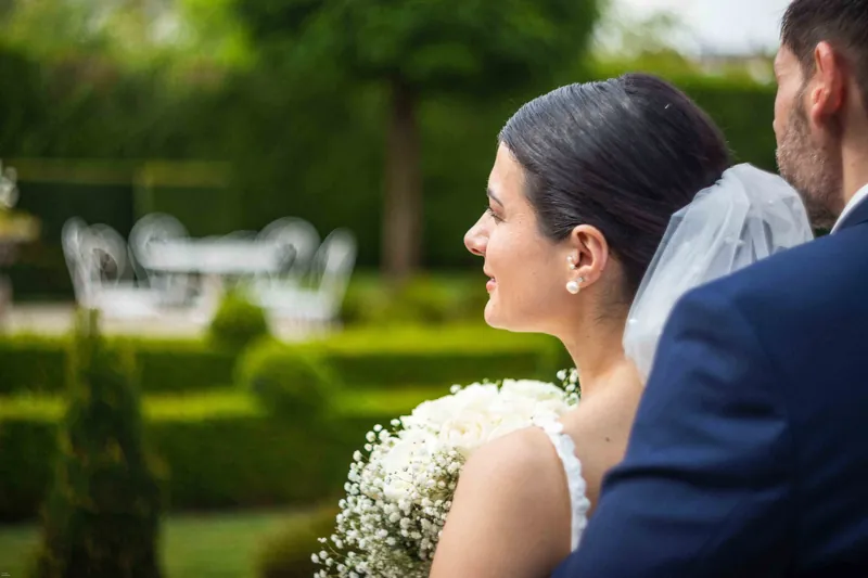 La mariée de profil, voile au vent, face au marié.