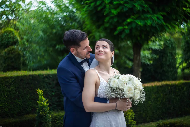 Les mariés se sourient dans un jardin à la française.
